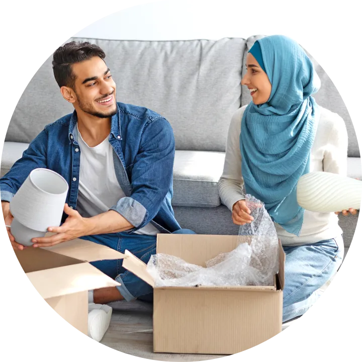 A man and a woman sitting on a couch with a box of toilet paper.