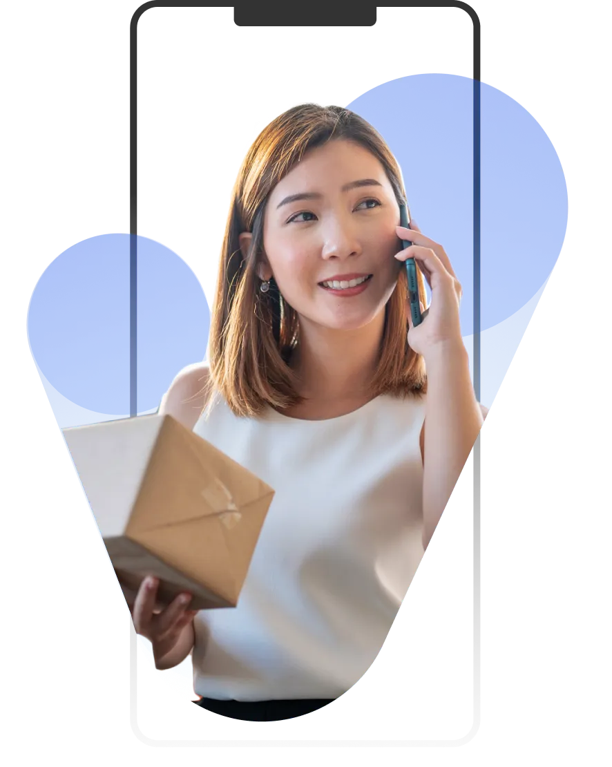 A woman talking on a cell phone while holding a box.