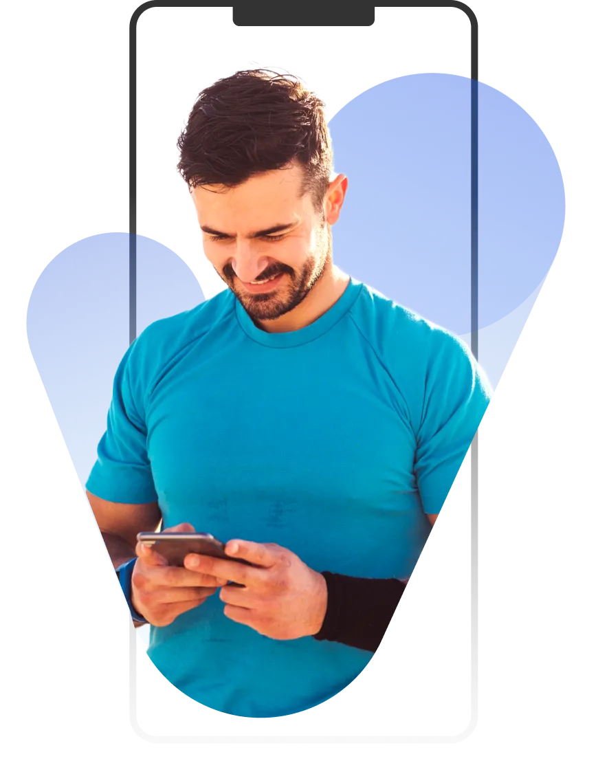 A man in a blue shirt looking at his cell phone.