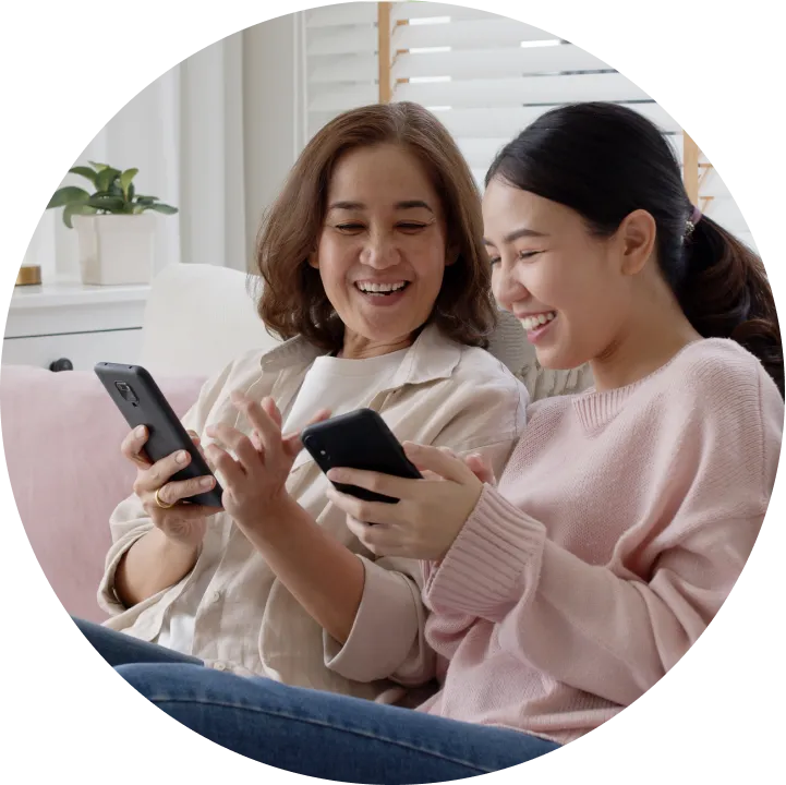 A couple of women sitting next to each other on a couch.