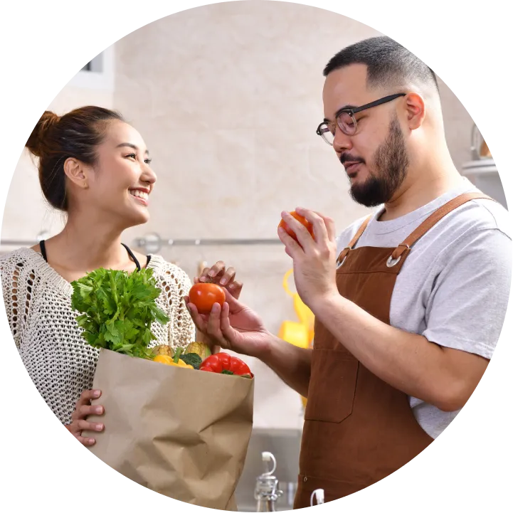 A man and a woman holding a bag of vegetables.